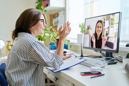 A person sitting at a desk taking part in a video call via a monitor